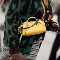 Gabriella Johnson wears grey sweater, yellow bag with bag charms and green and black striped dress outside the Chanel fashion show during the...