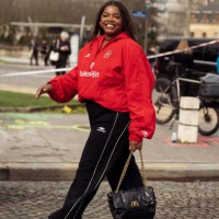Gabriella Karefa-Johnson wears black pants, red sport jacket from Balenciaga and black bag outside Balenciaga during the Womenswear Fall/Winter...