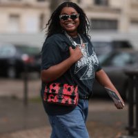 Gabriella Karefa Johnson is seen outside Chanel show wearing black and white Balenciaga sunnies, silver necklaces, grey vintage band t-shirt, long...