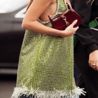 Gala Gonzalez wears a green sequined dress, wide-leg denim jeans, burgundy sunglasses, a burgundy bag and Rolex watch in gold outside Gucci during...