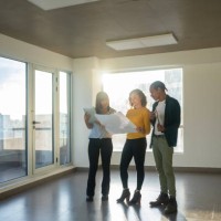 ganzkörperaufnahme einer architektin, die einem vielfältigen paar das renovierungsprojekt erklärt - home decoration stock-fotos und bilder