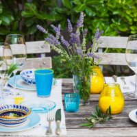 garden table laid with colorful plates and bowls - garden decoration stock pictures, royalty-free photos & images