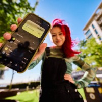 gen z adults outdoors with one person showing a smartphone displaying a bank balance and transactions. urban environment. low angle shot. - fashion stock pictures, royalty-free photos & images