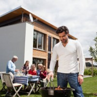 germany, bavaria, nuremberg, man cooking barbecue, family sitting in garden - garden decoration photos et images de collection
