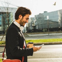 germany, frankfurt, young businessman walking the city with cup of coffee, using mobile phone - junk food stock pictures, royalty-free photos & images