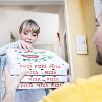 germany, north rhine westphalia, cologne, young woman taking pizza boxes from delivery man, smiling - junk food stock pictures, royalty-free photos & images