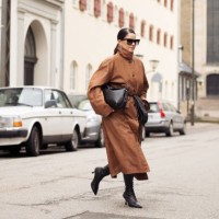 Gili Biegun wears, long brown leather coat, black bag, black long leather gloves, sunglasses and black shoes during the Copenhagen Fashion Week...