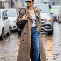 Gili Biegun wears long brown suede trench coat, denim jeans, black bag, creme white top and Gucci strappy sandals during the Milan Fashion Week...