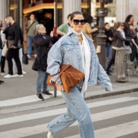 Gili Biegun wears white blouse, blue denim jacket, brown suede bag, sunglasses, golden necklace, blue jeans and white shoes outside the Vivienne...