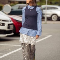 Ginevra Mavilla wears long shiny grey skirt, white shiny dress, blue shirt, navy blue tank top and green flip flops outside the Baum und Pferdgarten...