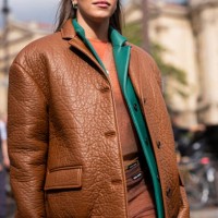 Ginevra Mavilla wears nude cardigan, green leather blazer, brown leather jacket and brown sheer skirt, outside Miu Miu, during the Womenswear...