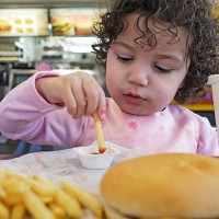 girl (2-3) sitting at table eating french fries, close-up - junk food stock pictures, royalty-free photos & images