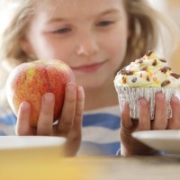 girl choosing between an apple and a cake - junk food stock pictures, royalty-free photos & images