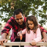 girl cutting wooden plank by father during summer - home decoration stock pictures, royalty-free photos & images
