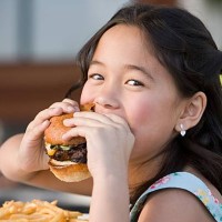 girl eating a burger - junk food stockfoto's en -beelden