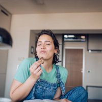 girl enjoying her favorite cookie at home - food stock pictures, royalty-free photos & images