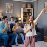 girl holding the remote controller as a microphone and performing at home - concert stock pictures, royalty-free photos & images