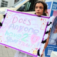 Girl holds up a sign asking if anyone has a spare ticket, as Taylor Swift fans, also known as 