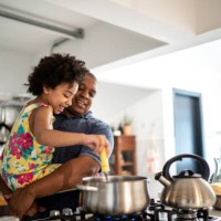 girl in father's arms helping him cooking at home - food stock pictures, royalty-free photos & images