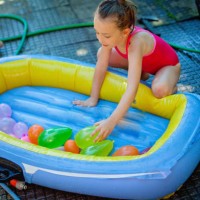 girl playing water balloons fight in summer - garden decoration stock pictures, royalty-free photos & images