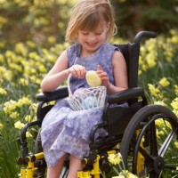 girl sitting on a wheelchair and holding a basket of easter eggs - garden decoration stock pictures, royalty-free photos & images