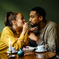 girlfriend feeding bite of dessert to her boyfriend at cafe - food stock pictures, royalty-free photos & images