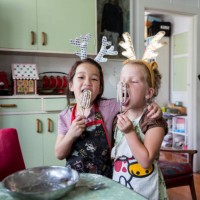 girls hugging and tasting mix from egg beater whilst preparing food for christmas - food stock pictures, royalty-free photos & images