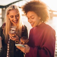 girls using phone and having a snack - junk food stock pictures, royalty-free photos & images