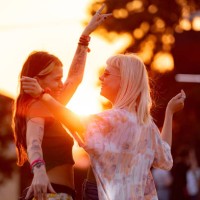 glückliche freundinnen, die sich während eines musikfestivals bei sonnenuntergang amüsieren. - concert stock-fotos und bilder