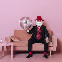 glamorous santa claus with disco ball sitting on sofa in pink room. concept fashion christmas party. - fashion stock pictures, royalty-free photos & images