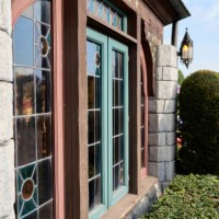 glass window and wooden frames, in stone wall, antique design, bushes and clear sky. - garden decoration stockfoto's en -beelden
