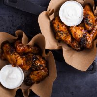 glazed spicy chicken wings with sesame seeds served in cast iron skillets - junk food stock pictures, royalty-free photos & images
