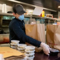 gloved and masked man in restaurant kitchen preparing food for delivery during covid-19 pandemic - junk food stock pictures, royalty-free photos & images