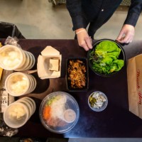 gloved man putting boxes of food in bags for delivery during covid-19 pandemic - junk food stock pictures, royalty-free photos & images