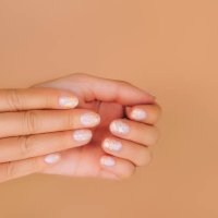 glowing hands with nude color manicure with gold particles on beige background. trendy colors of the year - nails art stock pictures, royalty-free photos & images