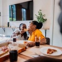 grandmother and granddaughter eating pizza at home - junk food stock pictures, royalty-free photos & images
