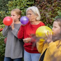grandmother and granddaughters blowing up balloons in garden together - garden decoration stock pictures, royalty-free photos & images