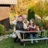 grandparents and granddaughter sitting at garden table crafting with mountain ash - garden decoration stock pictures, royalty-free photos & images
