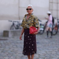 Grece Ghanem is seen wearing oval tortoiseshell sunglasses from Prada, red hoop earrings with a white dot pattern, a shirt with wide sleeves in a...