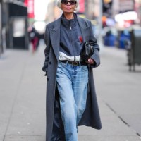 Grece Ghanem wears black sunglasses, dark navy blue white zipped high neck jacket, dark blue double breasted wool coat, shiny black Calvin Klien...