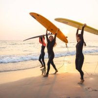 group of female surfers walking on the beach - travel stock-fotos und bilder