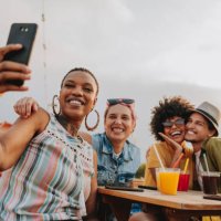 group of friends at table taking selfie - travel stockfoto's en -beelden