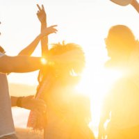 group of friends dancing and celebrating on the beach at sunrise/sunset. - concert stock pictures, royalty-free photos & images