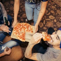 group of friends eating pizza and drinking beer at party - junk food stock pictures, royalty-free photos & images