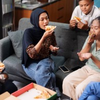 group of friends enjoying pizza together in casual indoor setting - junk food stock pictures, royalty-free photos & images