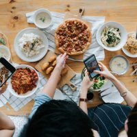 group of friends taking pictures of food on the table with smartphones during party - food stock pictures, royalty-free photos & images