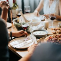 group of joyful young asian man and woman having fun, enjoying food and wine across table during party - food stock pictures, royalty-free photos & images
