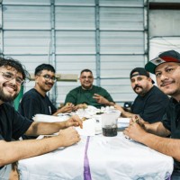 group of latino males having lunch at auto body paint shop - junk food stock pictures, royalty-free photos & images