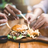 group of young people enjoying home party with hamburger and french fries. - junk food stock pictures, royalty-free photos & images