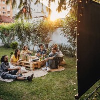 groupe d’amis se réunissant, regardant un film sur projecteur dans le jardin et traînant - garden decoration photos et images de collection